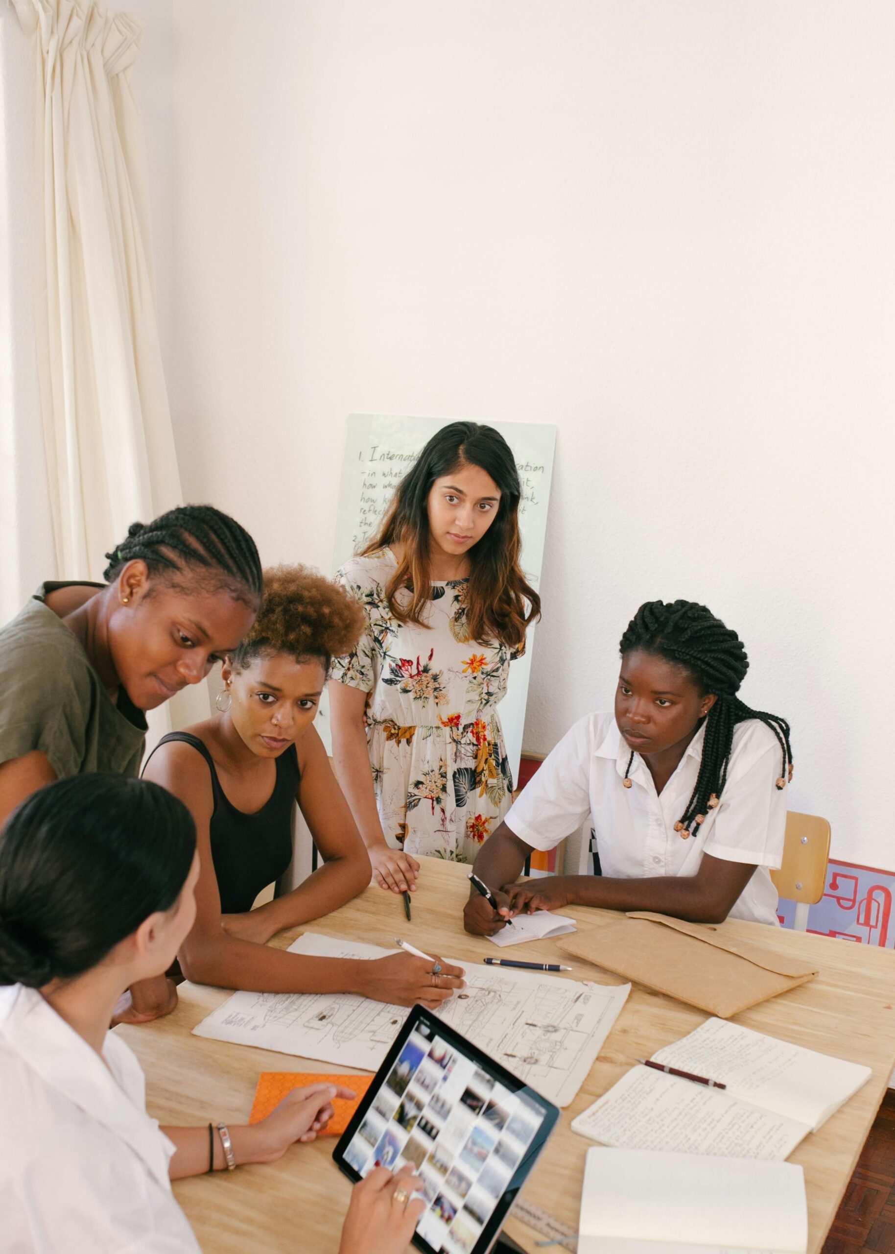 A diverse group of women discussing a project in a modern office setting.
